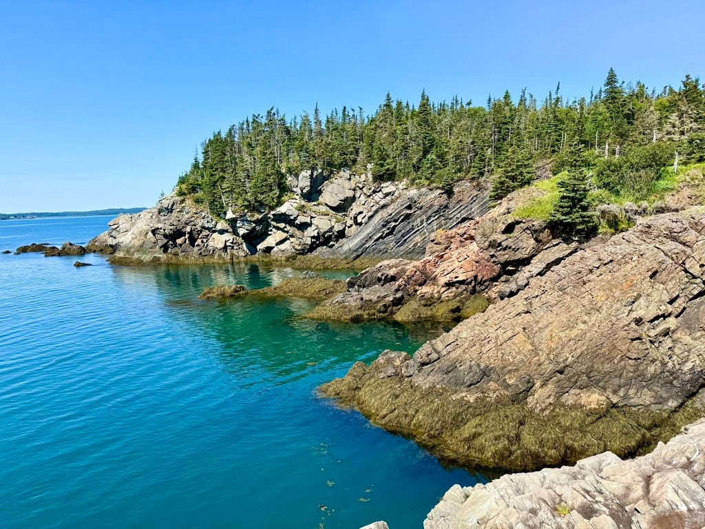 Rocky Liberty Point shoreline with clear turquoise water and a bright blue sky