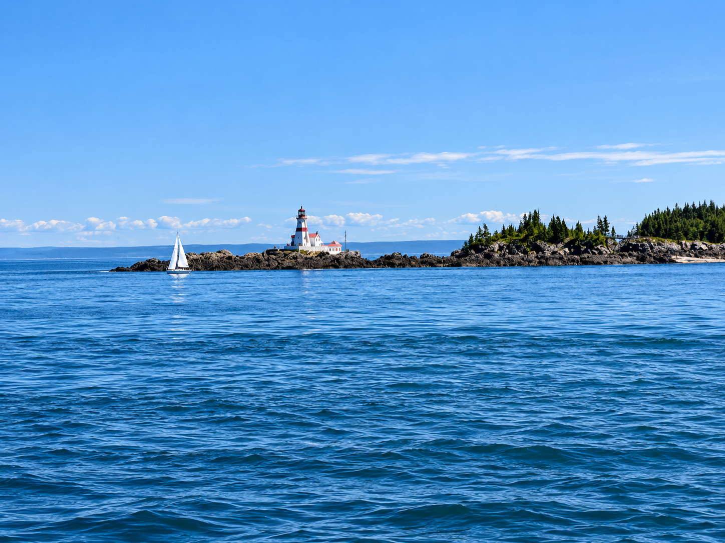 Head Harbor Lighthouse on Campobello Island with a sailboat nearby