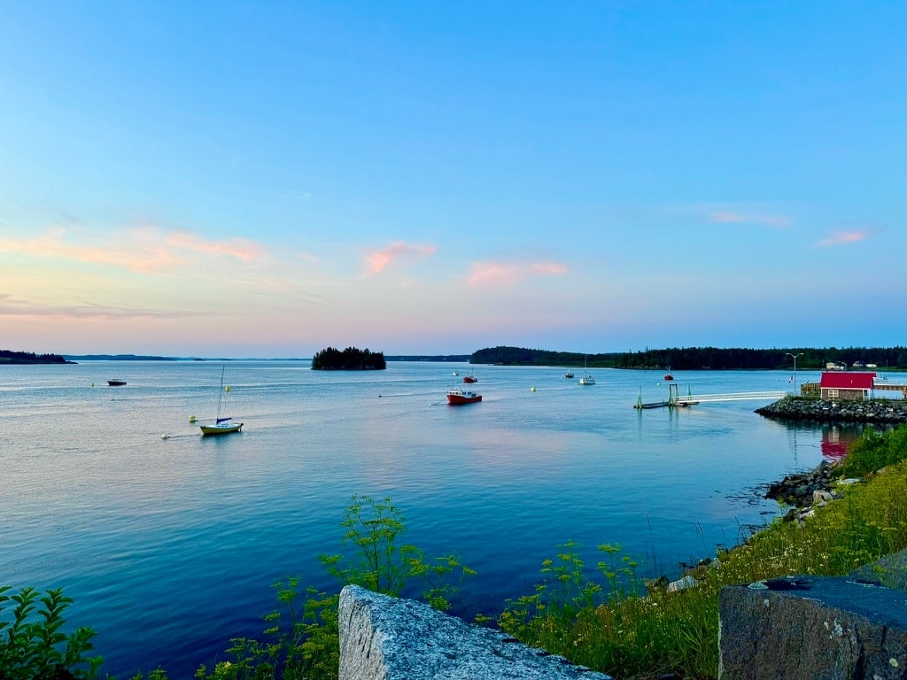 Calm Lubec harbor at sunset with boats and small islands