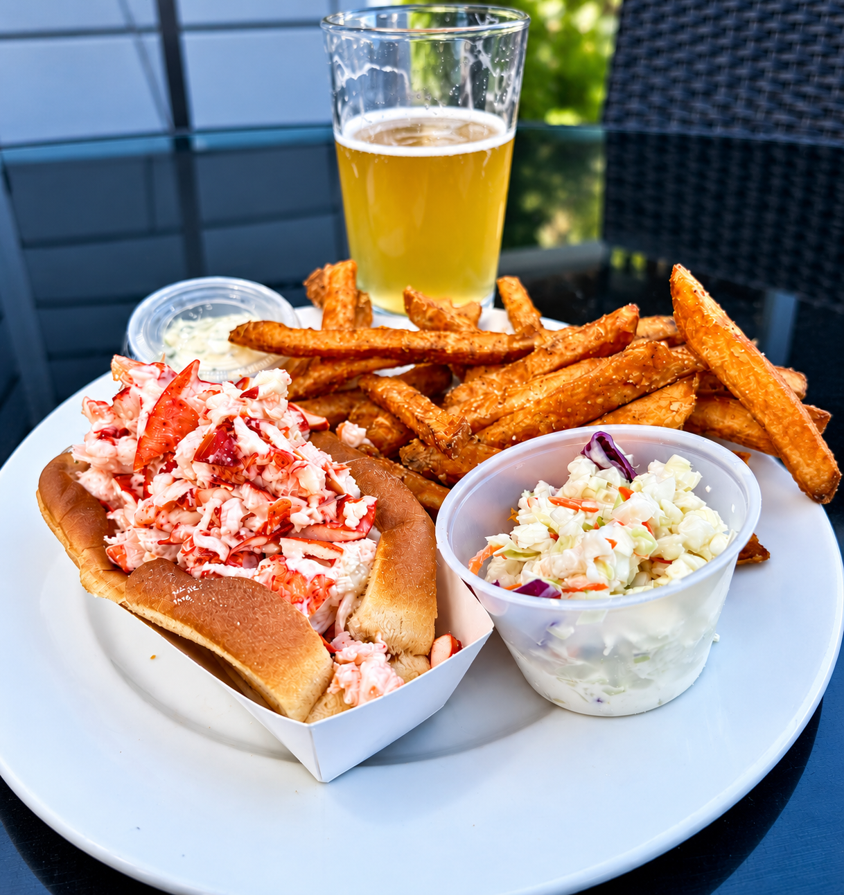 Lobster roll with fries, coleslaw, and a beer at Fisherman's Wharf Restaurant