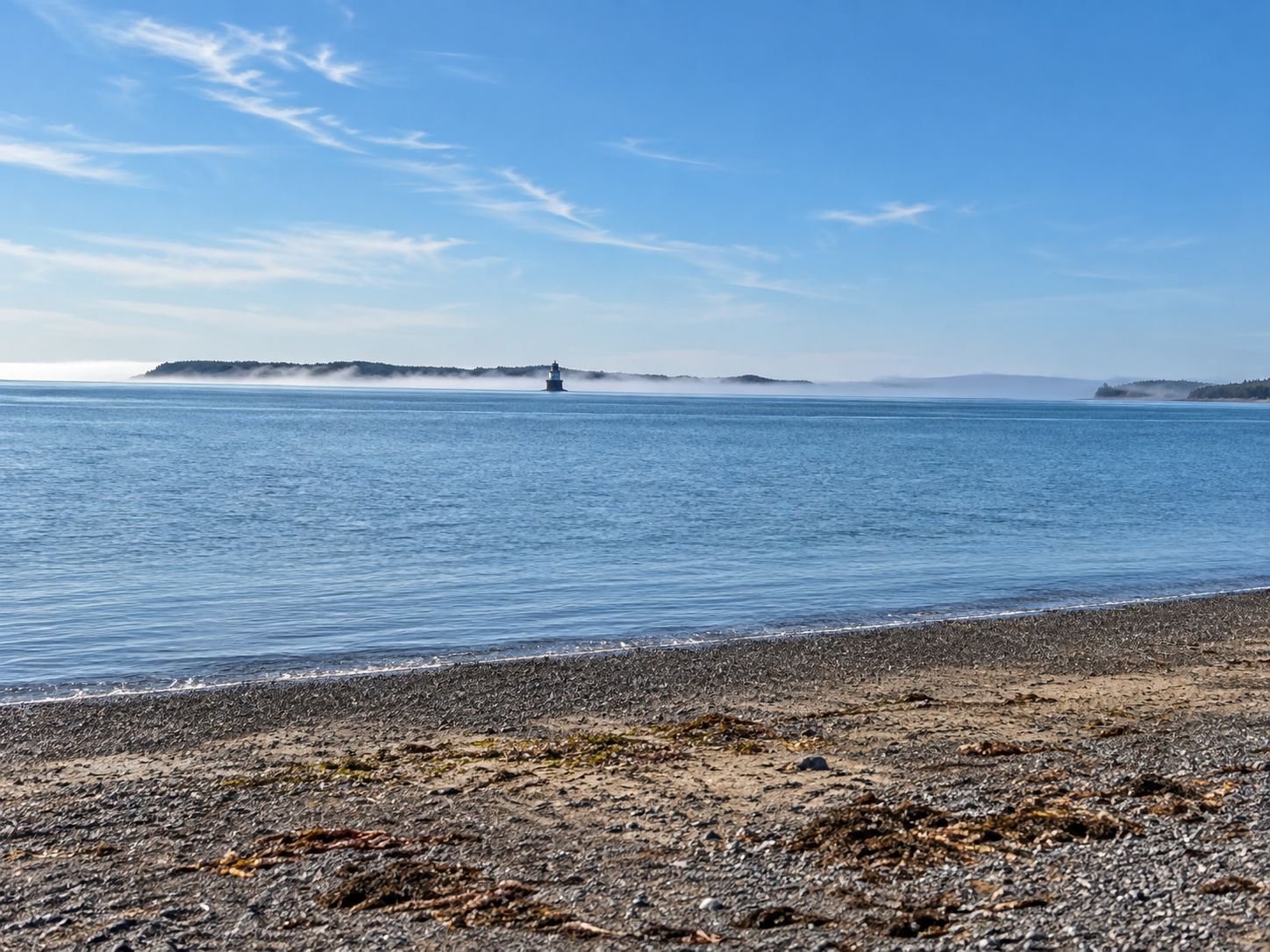 Calm blue water and a distant channel lighthouse along the Lubec coast